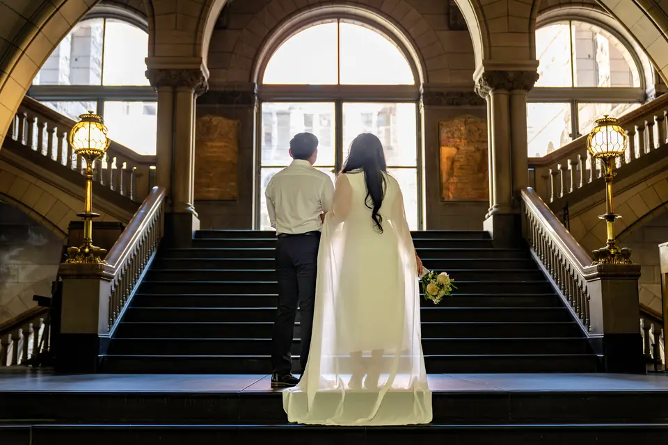 Couple standing at the top of the grand staircase inside the Allegheny County Courthouse