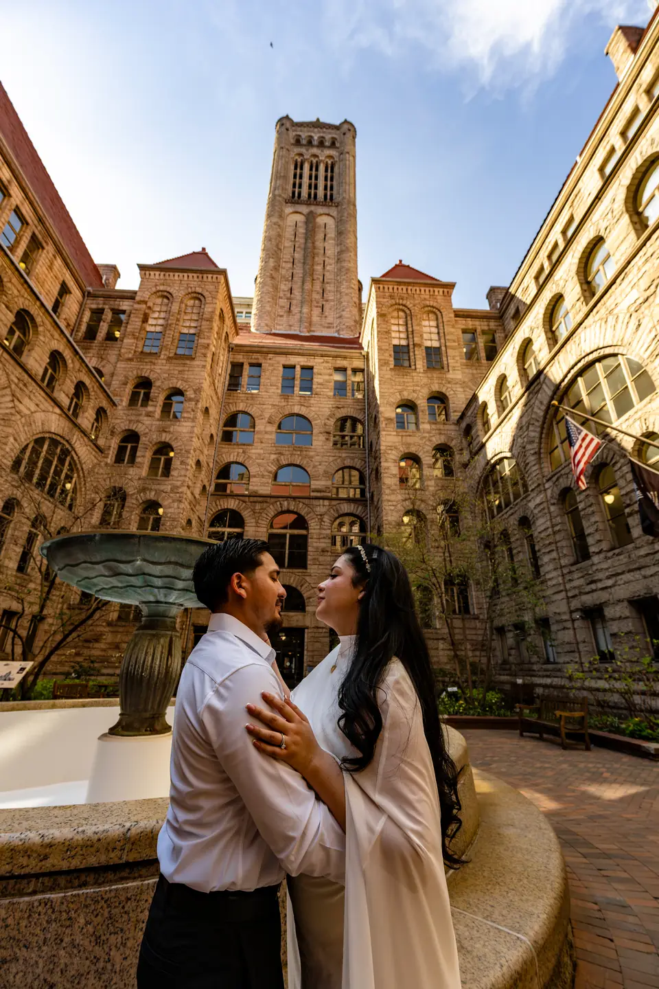 Couple holding hands in the stone courtyard of the Allegheny County Courthouse at golden hour