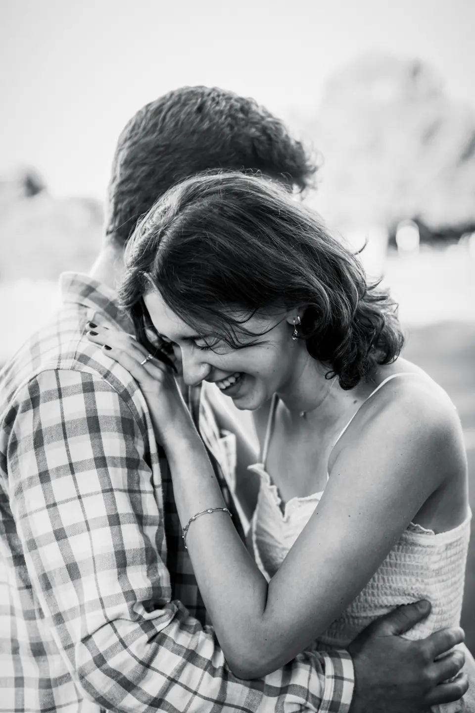 Black and white engagement photo of a couple laughing in a close embrace