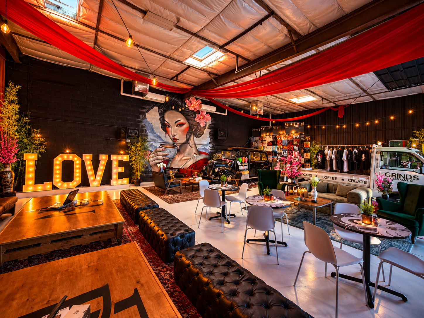 Grinds Garage lounge with a Japanese geisha mural, illuminated LOVE letters, red fabric overhead, leather seating and a coffee setup
