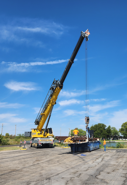 Large crane mobilizing IET barge drilling platform onto waterway