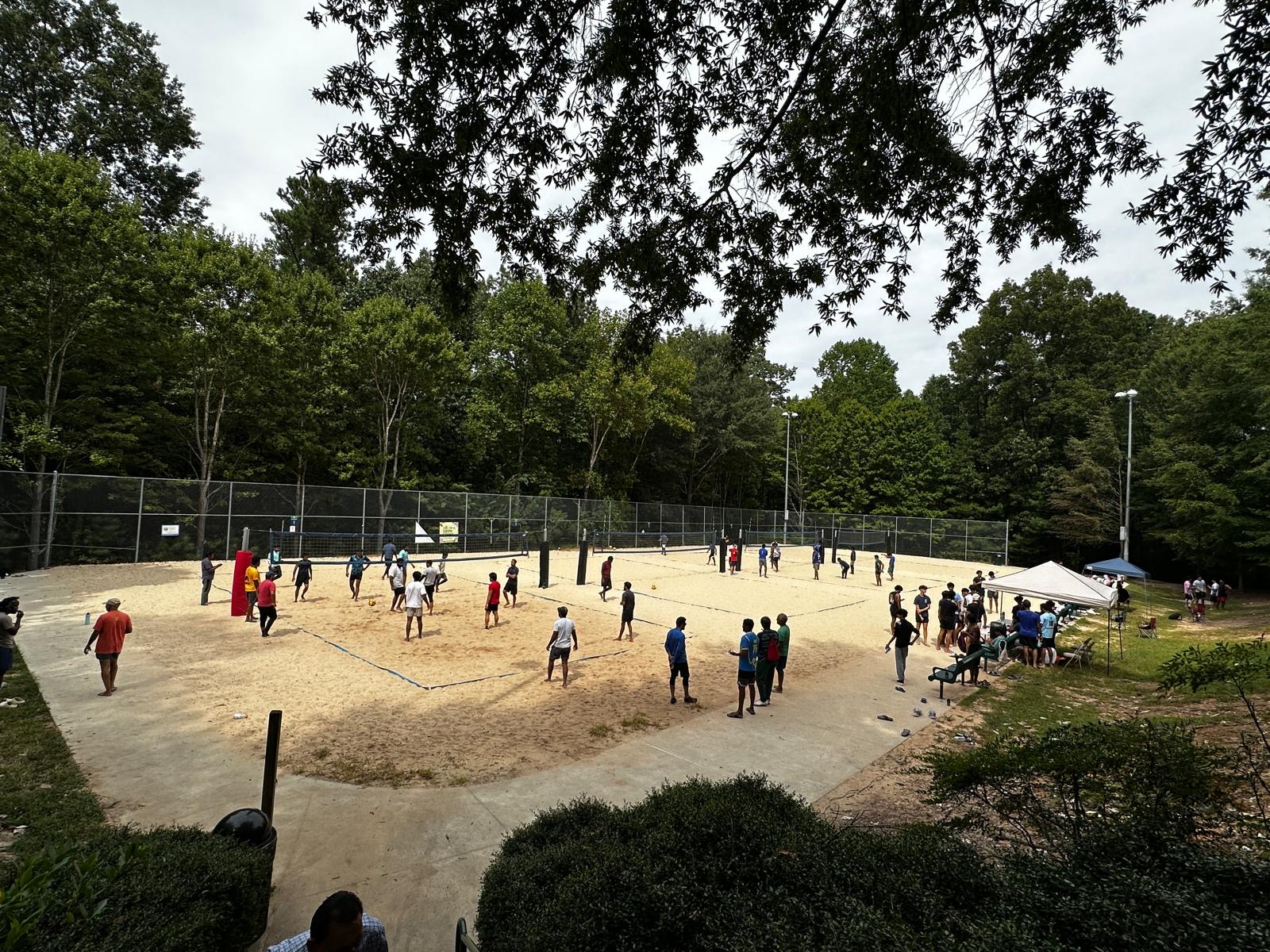 Sand volleyball courts surrounded by trees during a tournament