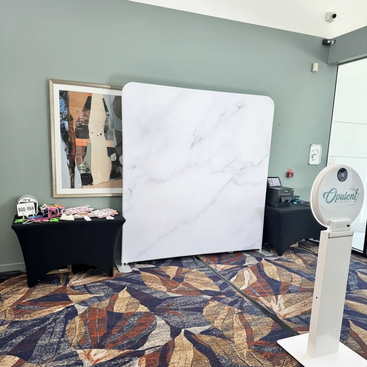 Open-air photo booth with a marble-print backdrop and prop table