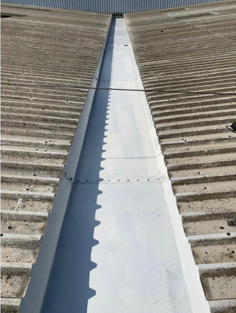 Flat commercial roof refurbishment — TopSpray35 coating applied to flat roof deck area with scaffolding present