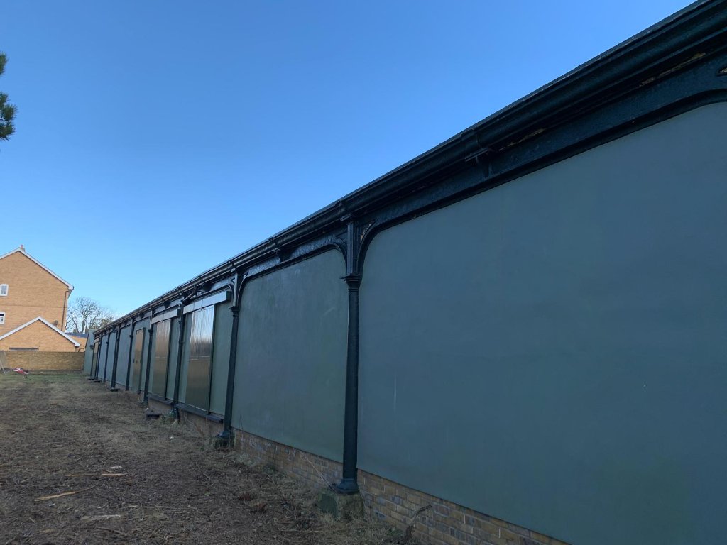 Metal structure coating — small corrugated metal building coated at night, dark graphite finish
