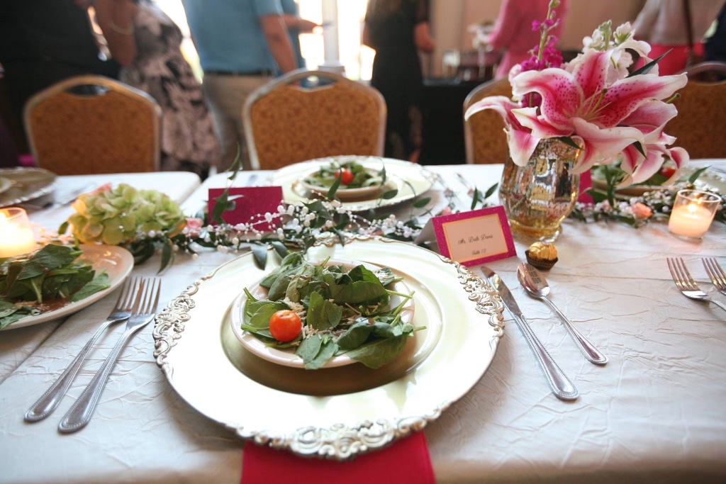 Elegant place setting with a pre-set salad on a silver charger and a personalized place card