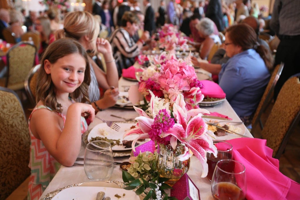 A guest enjoying dinner at a beautifully set table with pink lily centerpieces