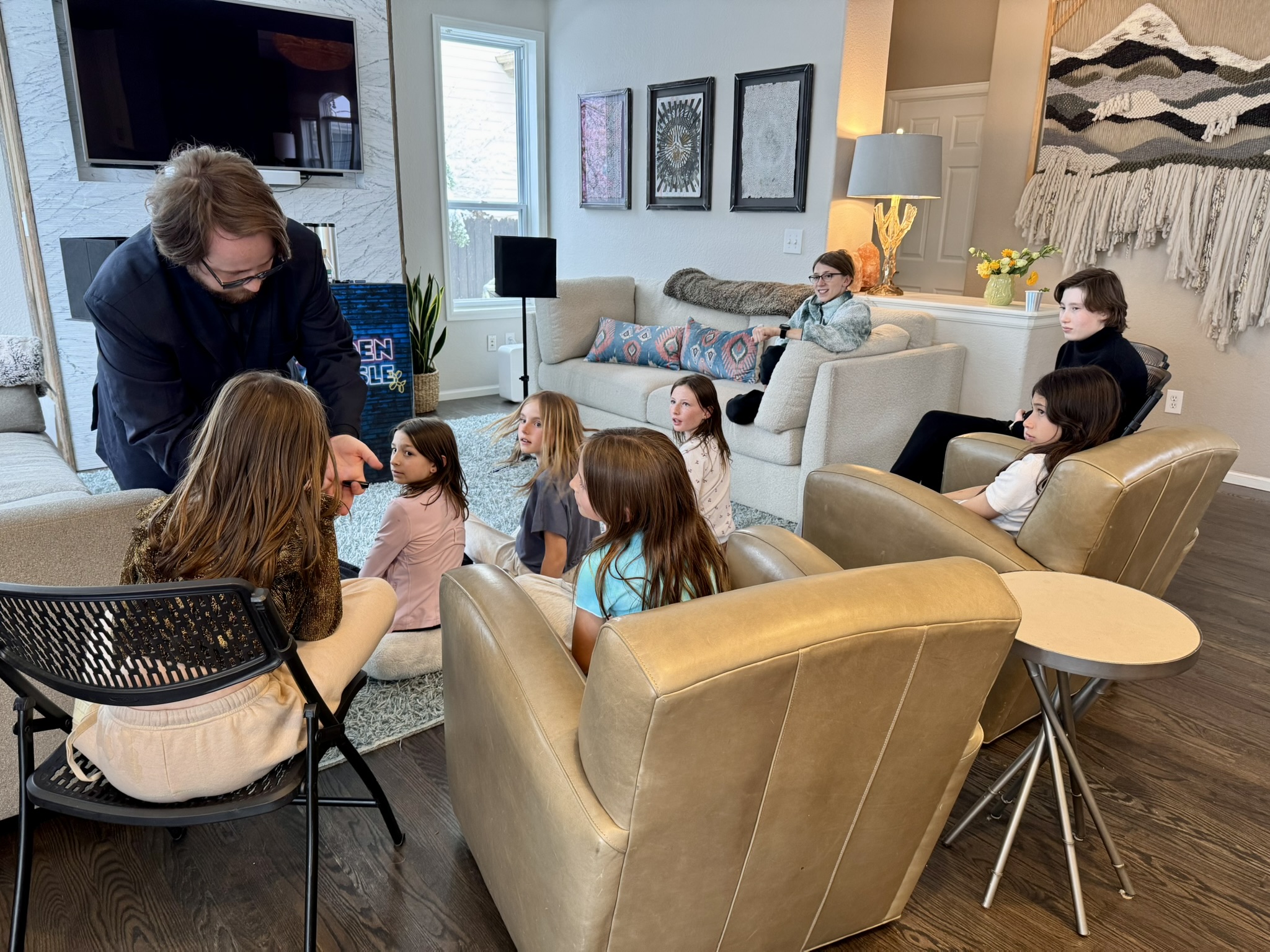 Children sitting on a living room rug watching Braden Carlisle perform magic at a birthday party