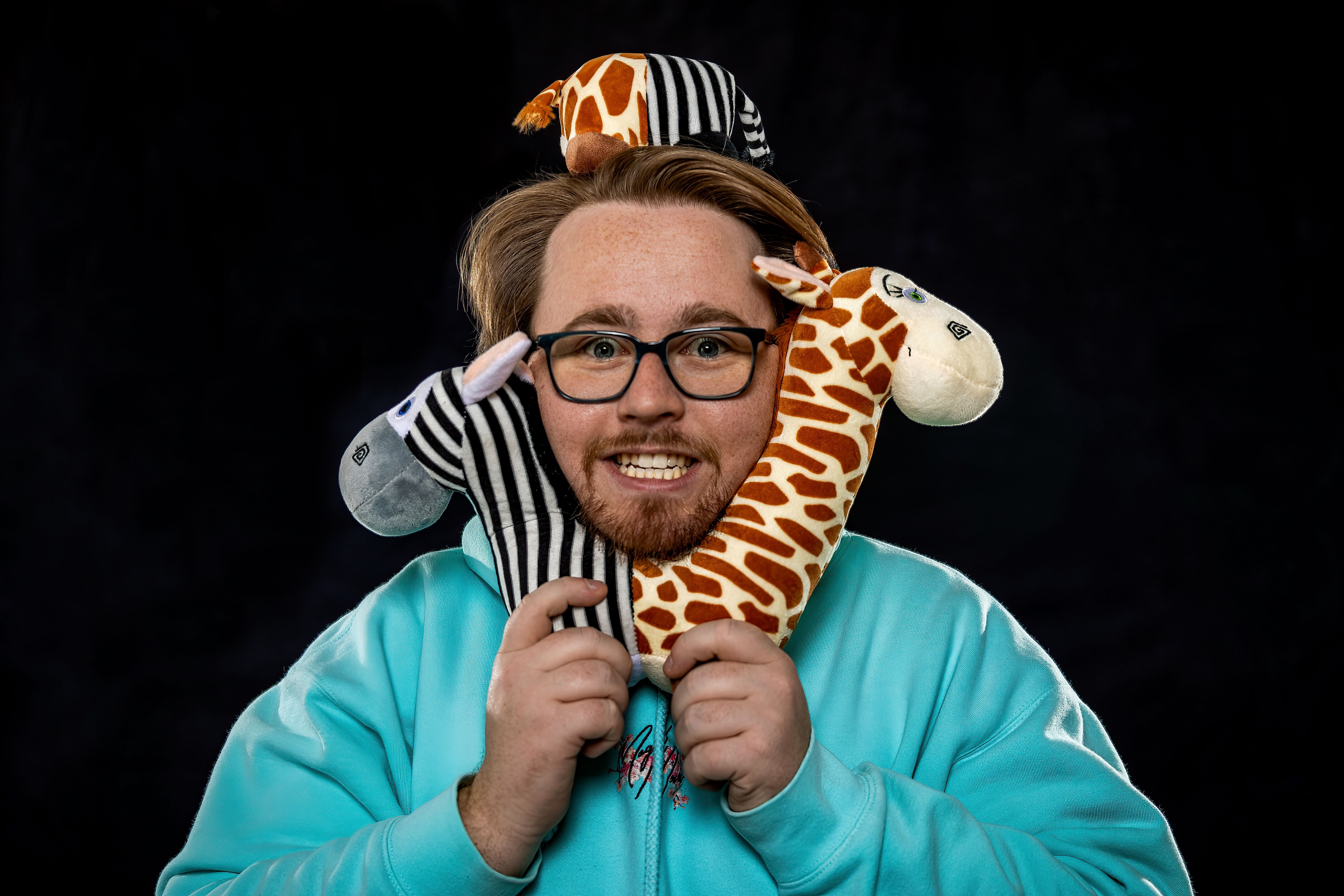 Braden Carlisle smiling beside plush toys, moments before a young guest reacts to a live magic trick
