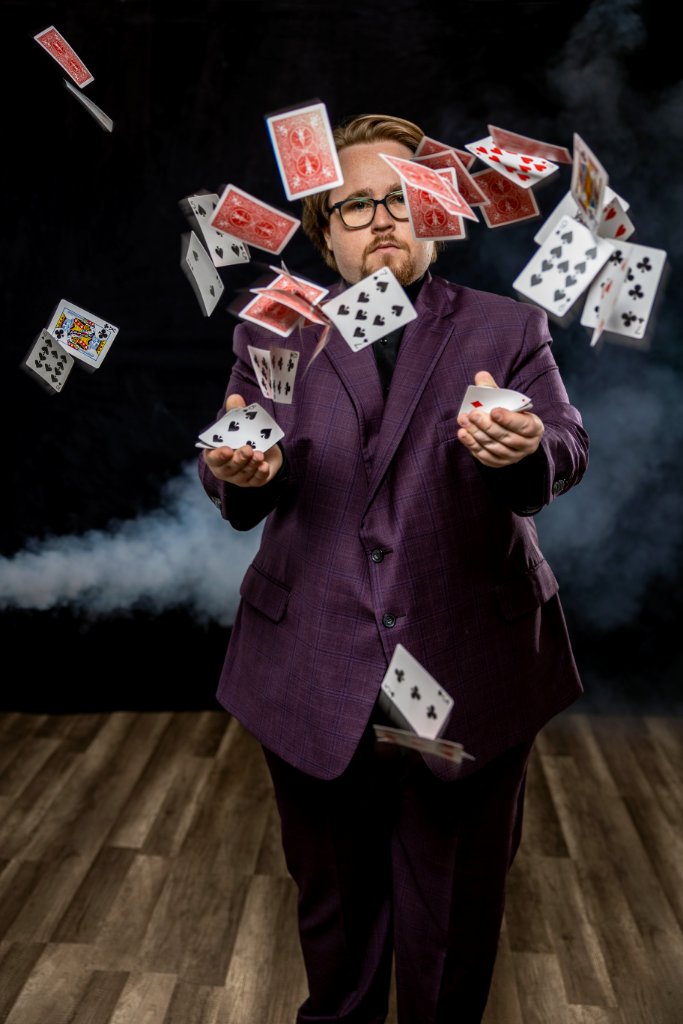 Braden Carlisle performing a card toss against a black backdrop