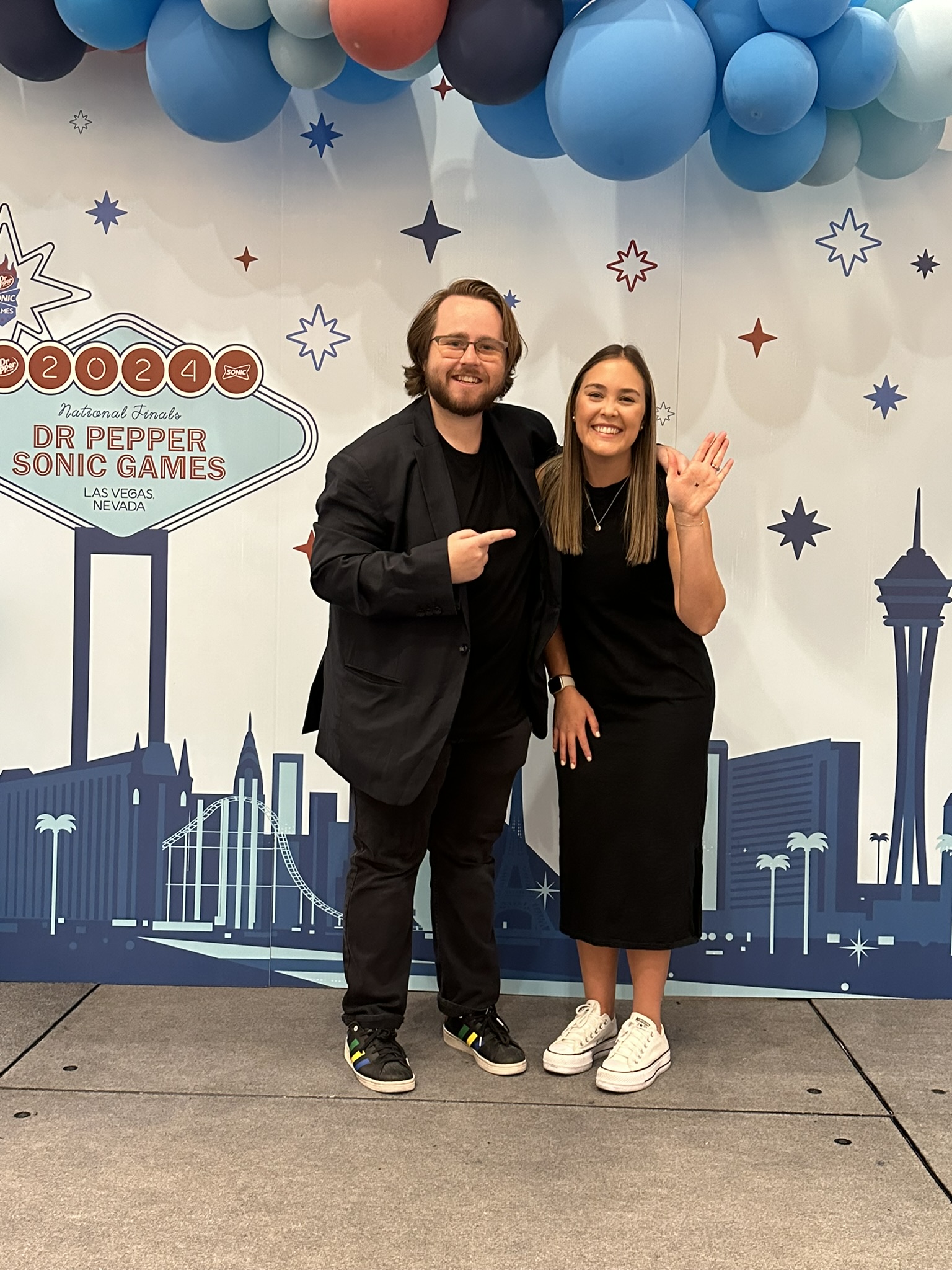 Braden Carlisle posing with a Sonic Drive-In National Finals winner in front of the Dr Pepper Sonic Games Las Vegas backdrop