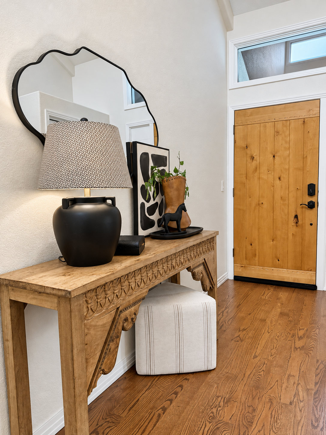 Entryway of 10276 Totem Run with rustic wood front door, console table and organic mirror — Roxborough Park Littleton home for sale