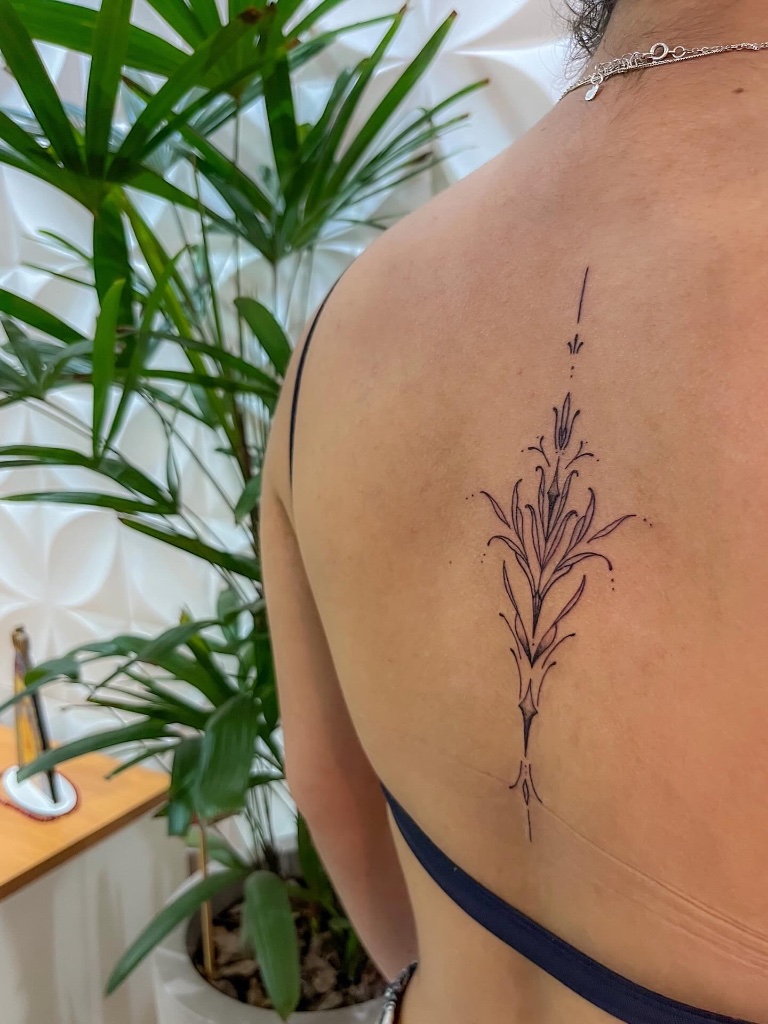 Fine-line floral spine tattoo