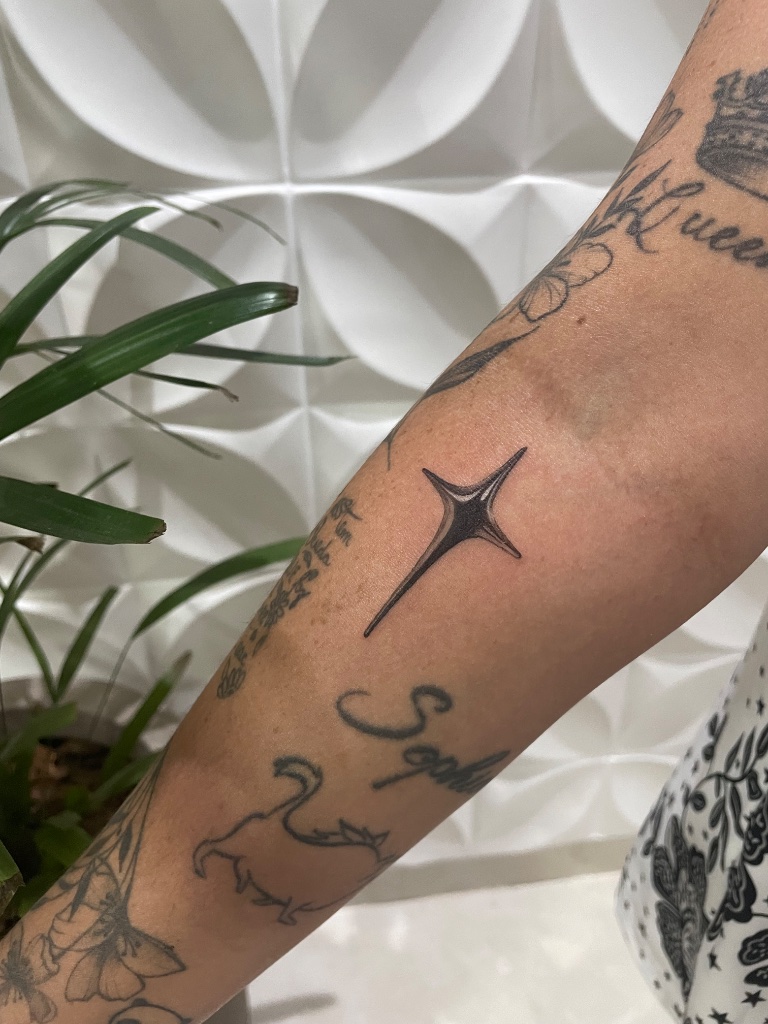 Four-pointed star tattoo on forearm