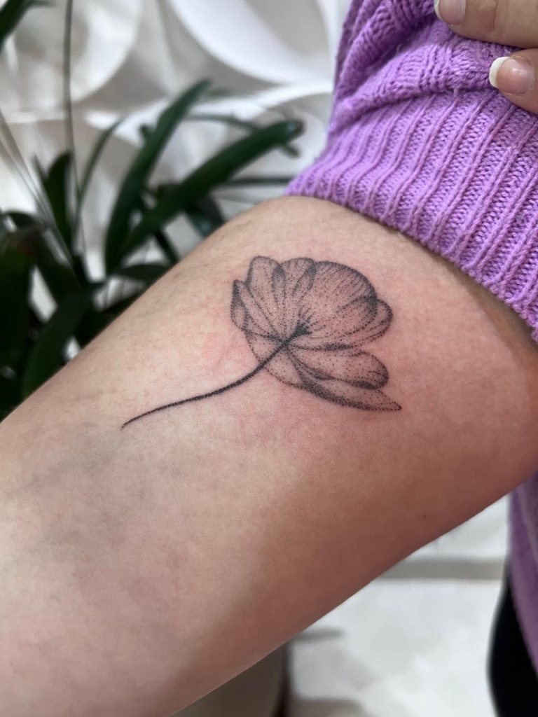 Fine-line flower tattoo on arm