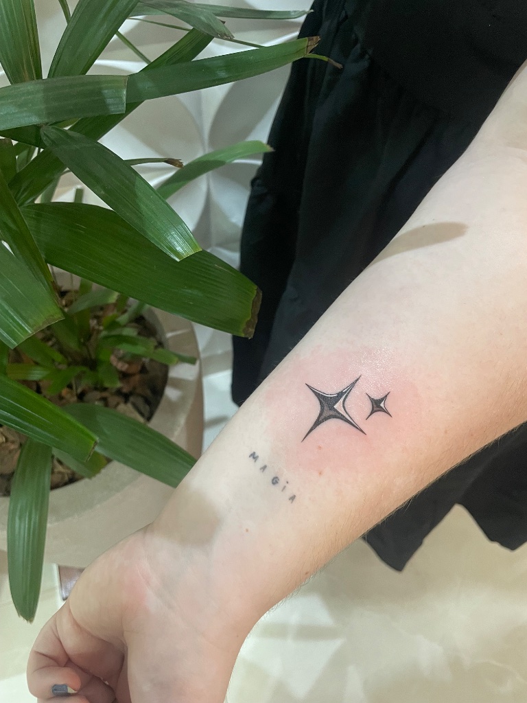 Stars and MAGIA lettering tattoo on wrist