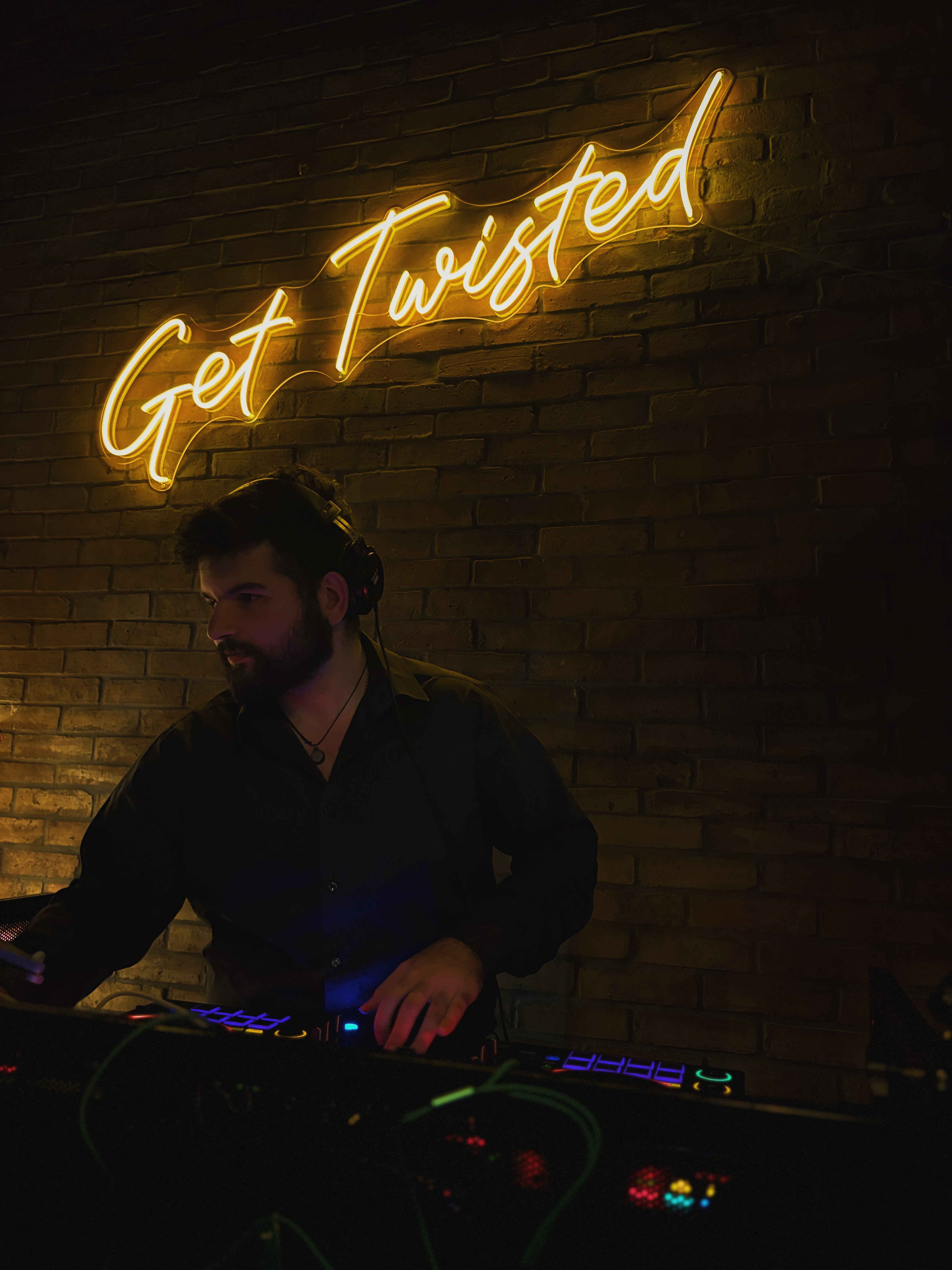 RogueMen Entertainment DJ performing in front of a glowing neon sign at a live event