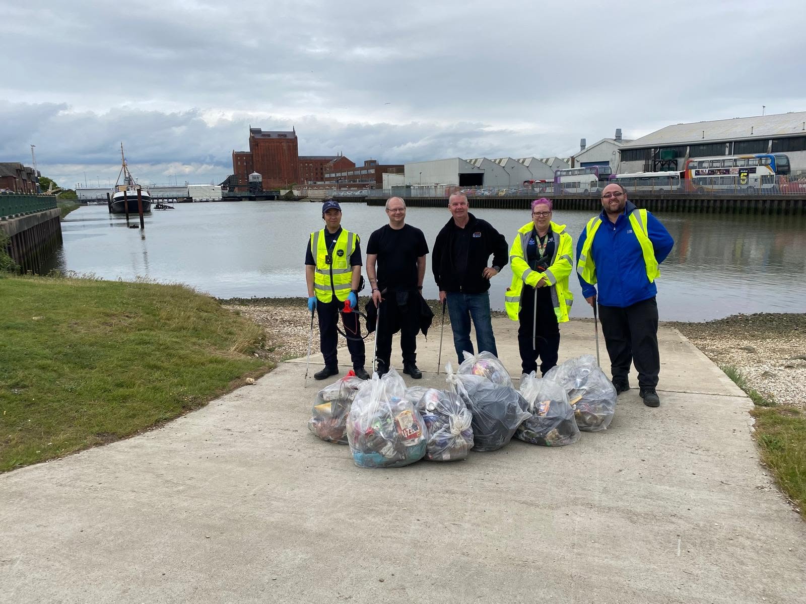Volunteers with bags of litter collected during a riverside clean-up
