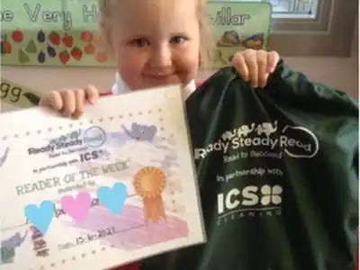 Pupil holding a Reader of the Week certificate and a Ready Steady Read book bag in partnership with ICS Cleaning