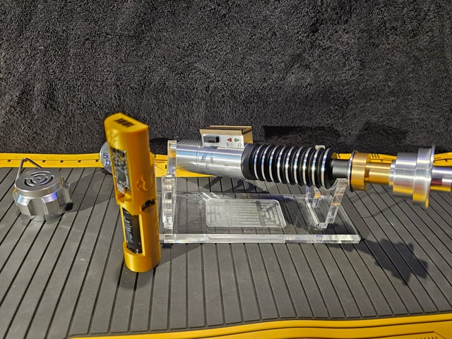 A removable power core beside its hilt — the core slides out as a single self-contained unit.