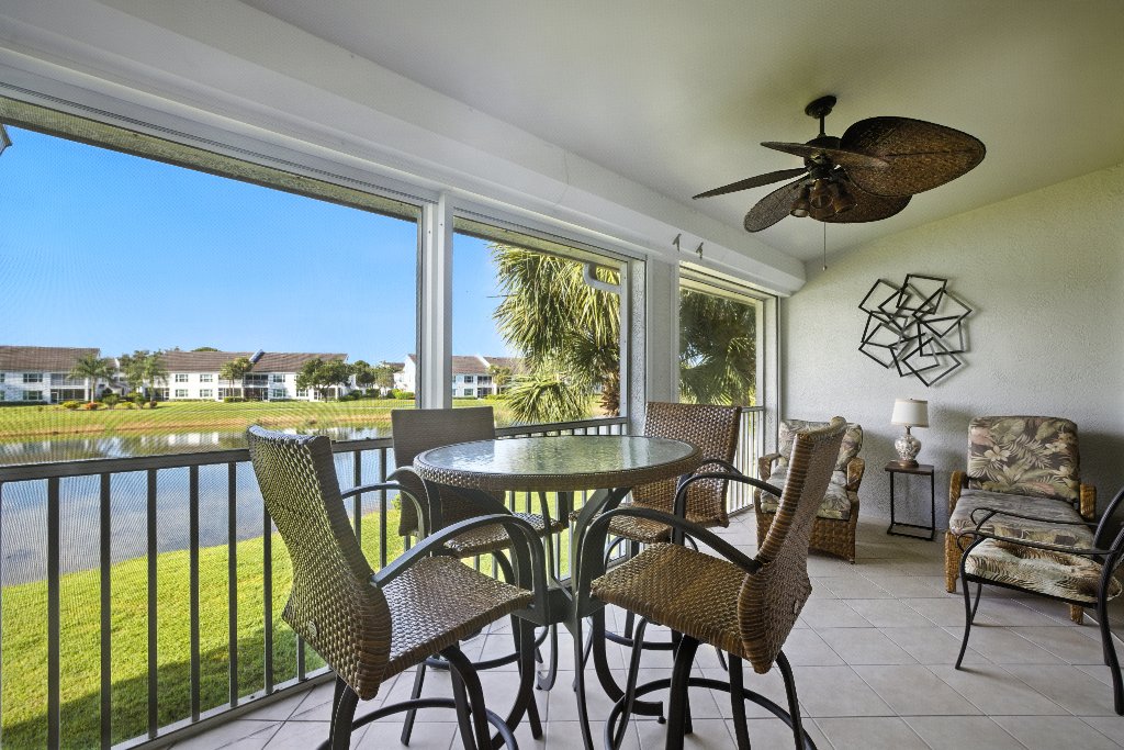 Lanai dining area with wicker bar seating overlooking golf course lake at Pinnacle, Unit 2503 Naples FL