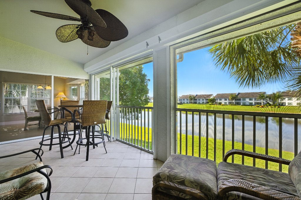 Enclosed lanai with wicker seating and panoramic golf course and lake views at Pinnacle, Unit 2503 Naples FL
