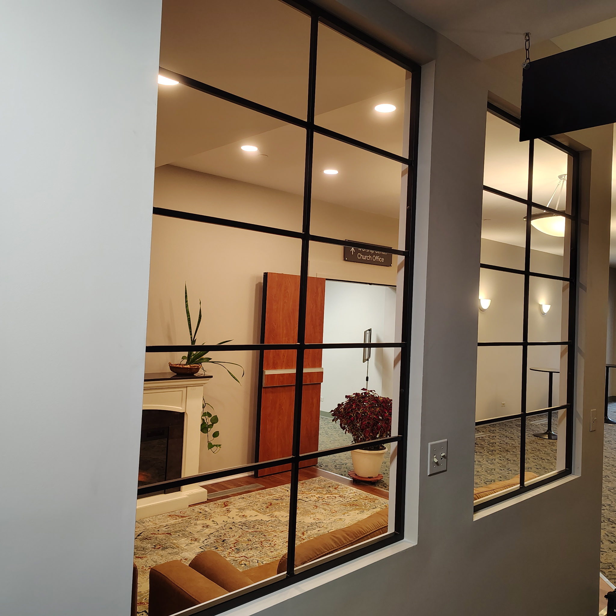 Floor-to-ceiling black metal grid partition dividing an interior space.