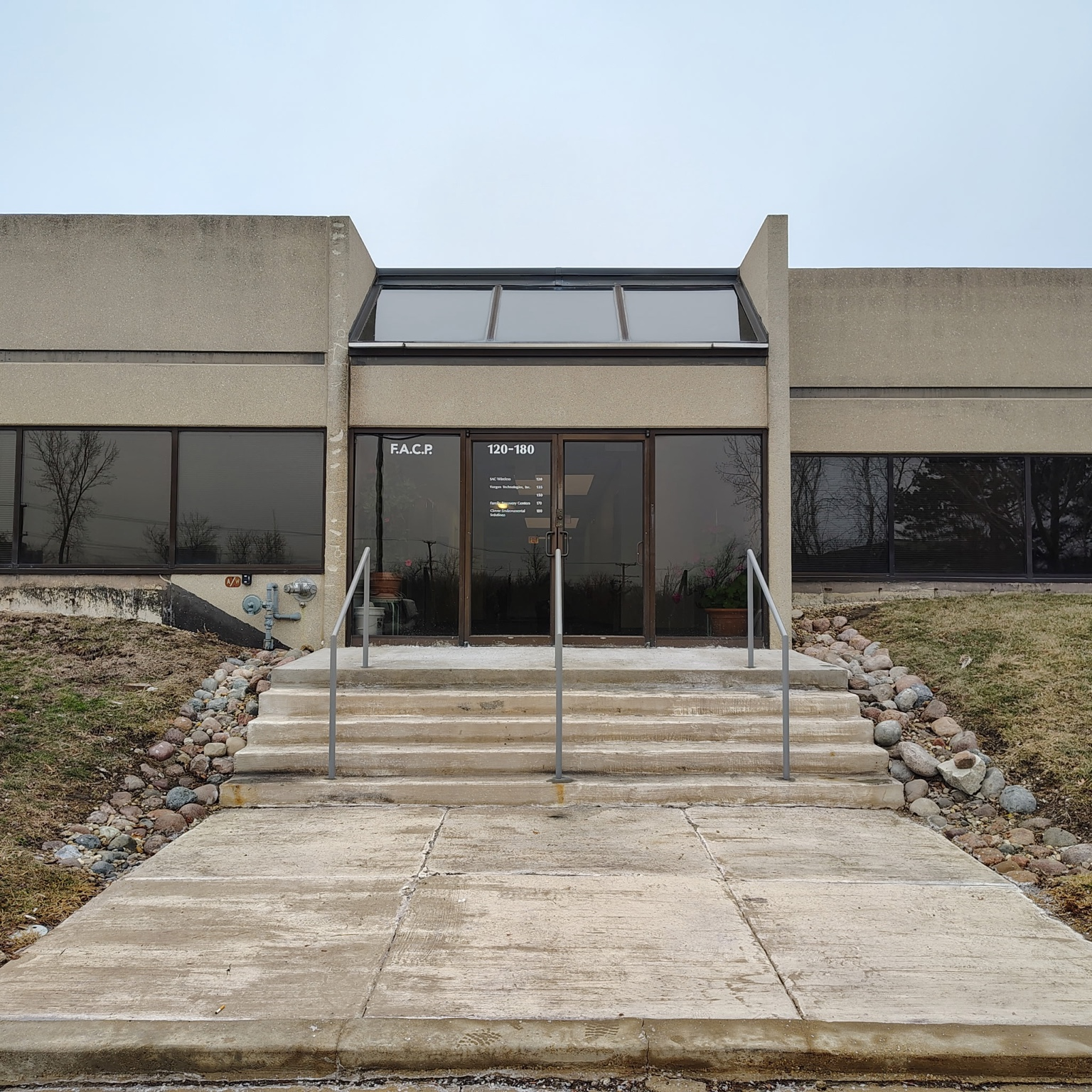 Metal handrails lining concrete steps at a commercial building entrance.