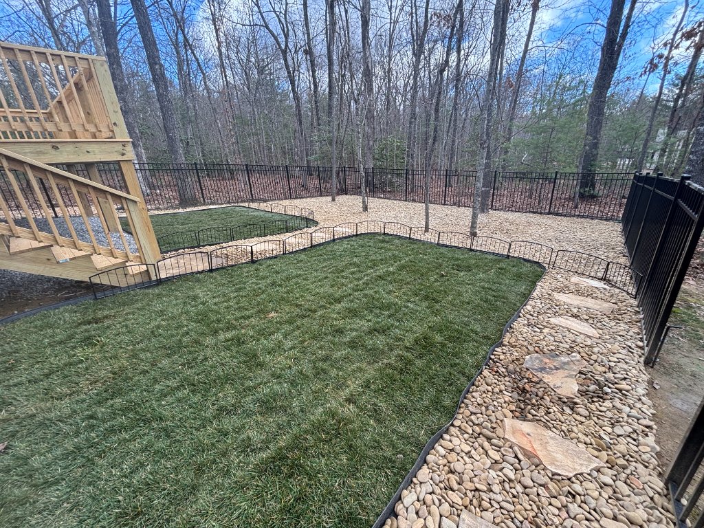 Sod installation with decorative rock border and metal fencing