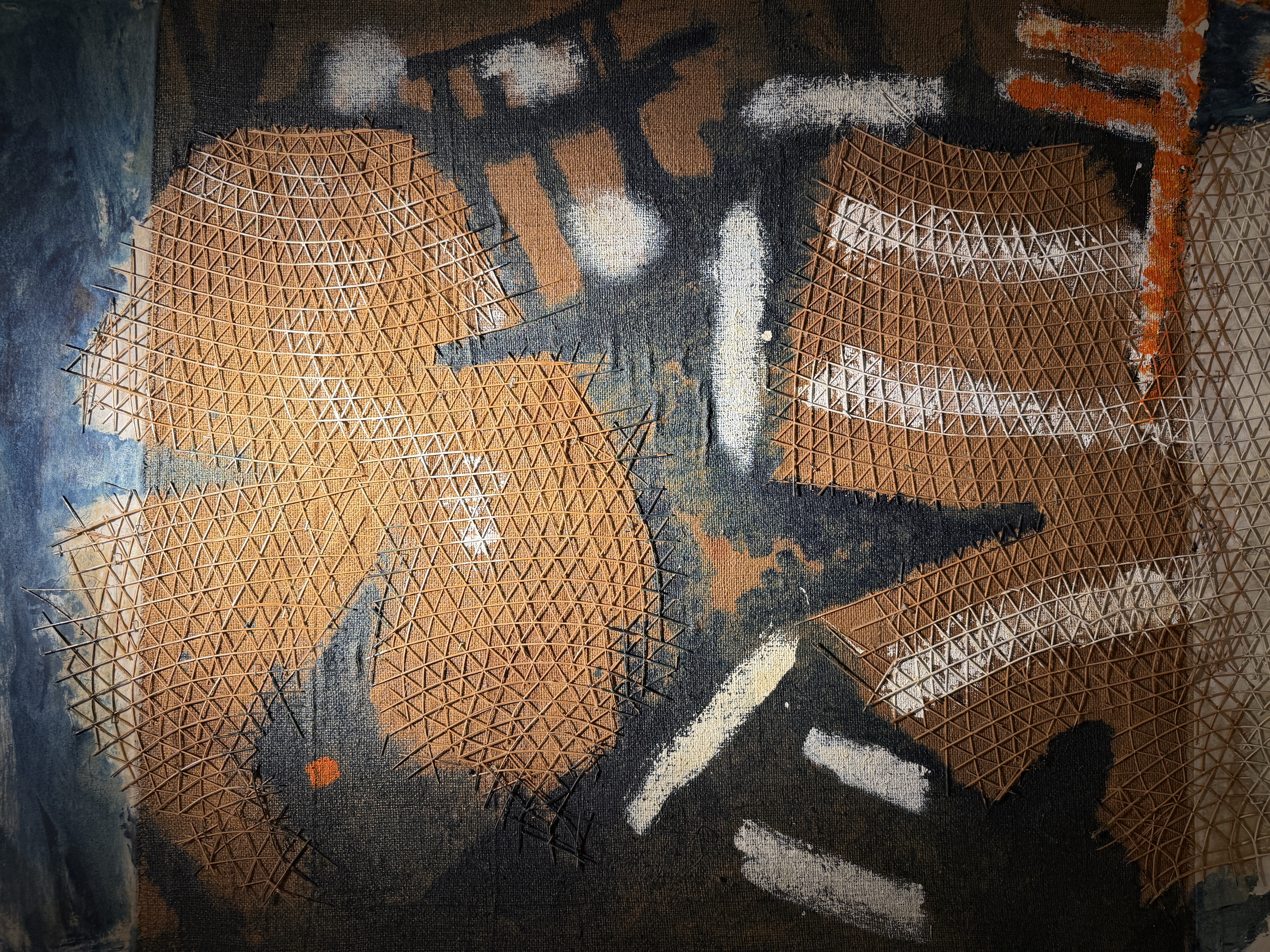 Abstract mixed-media painting by Gabriel Caruana with dark charcoal canvas orange white strokes and beige wire mesh lattice at the Victor Passmore Gallery