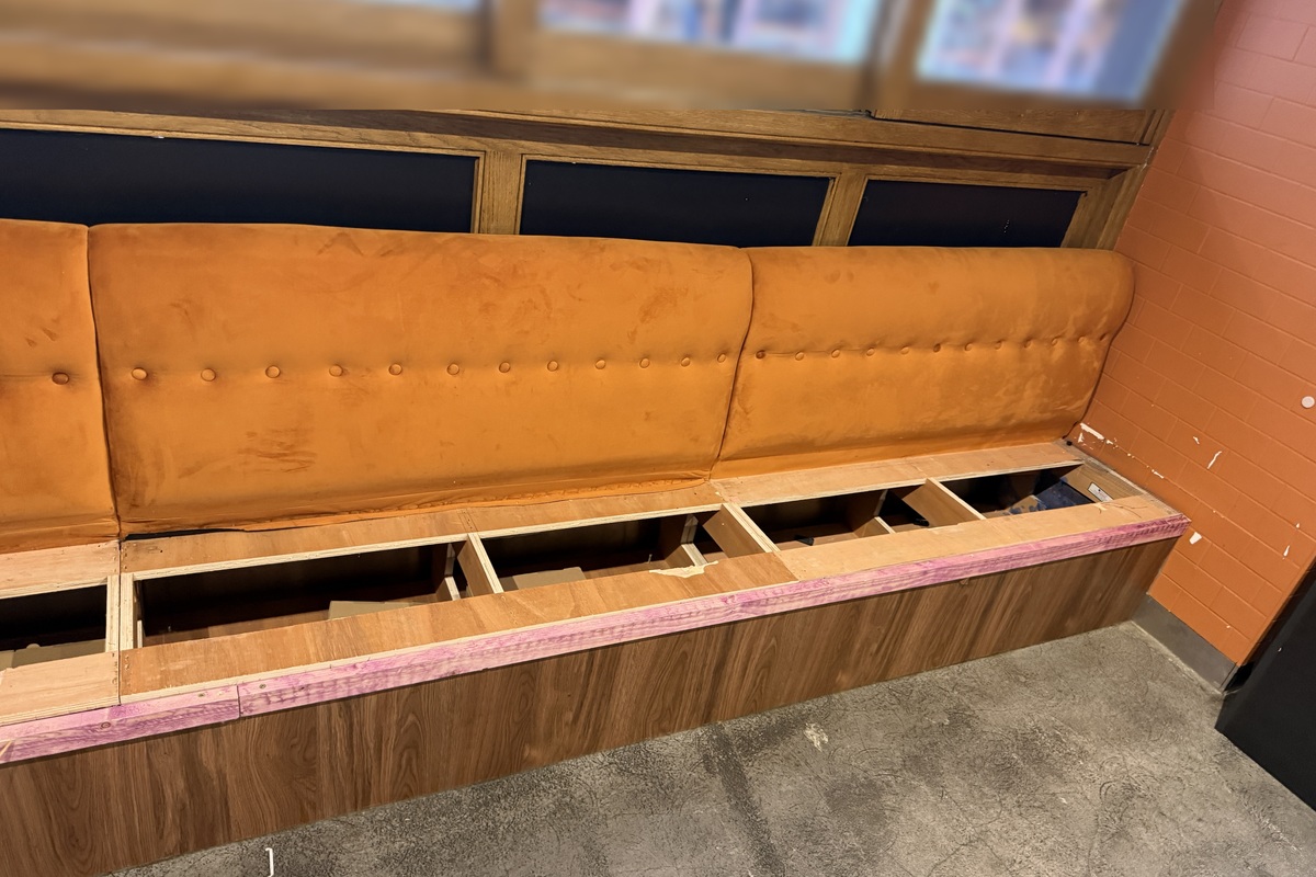 Booth seating being dismantled for reuse during a restaurant closure clearance