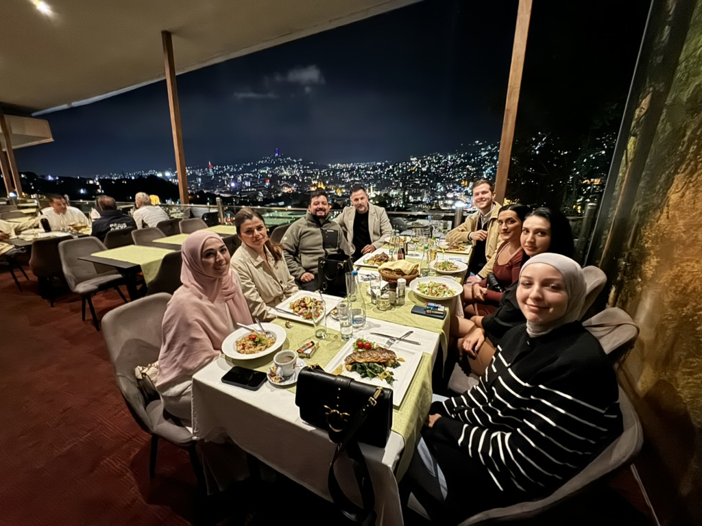 Team auf einer Terrasse mit Blick auf eine Stadt bei Nacht