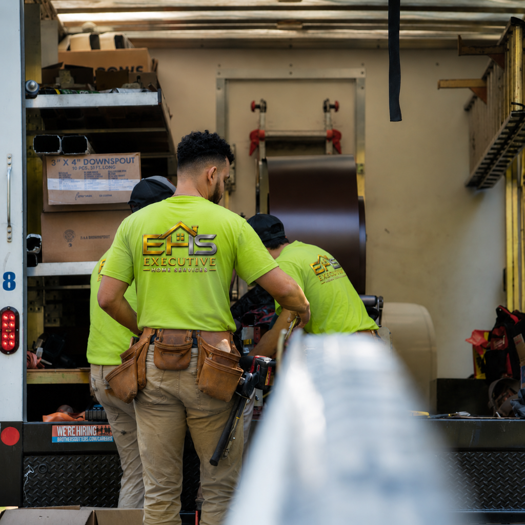 Executive Home Services crew loading seamless gutter and downspout material rolls in the service truck