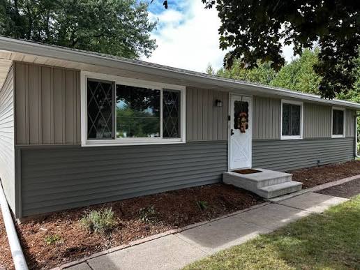 Single-story home with a two-tone horizontal siding installation, light tan above and darker slate below, separated by white trim