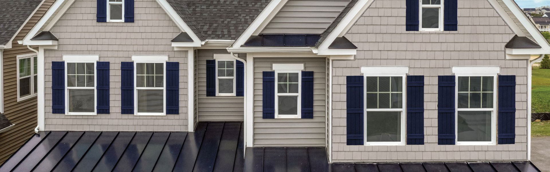 Two-story home with light grey shake-style shingles on the gables and horizontal lap siding below, navy shutters and white trim