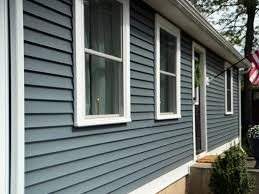 Close-up of slate blue-grey horizontal lap siding with bright white window frames and a white trim board
