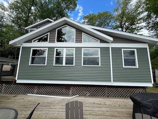 Single-story home with muted olive-green horizontal siding, white trim and a triangular window arrangement