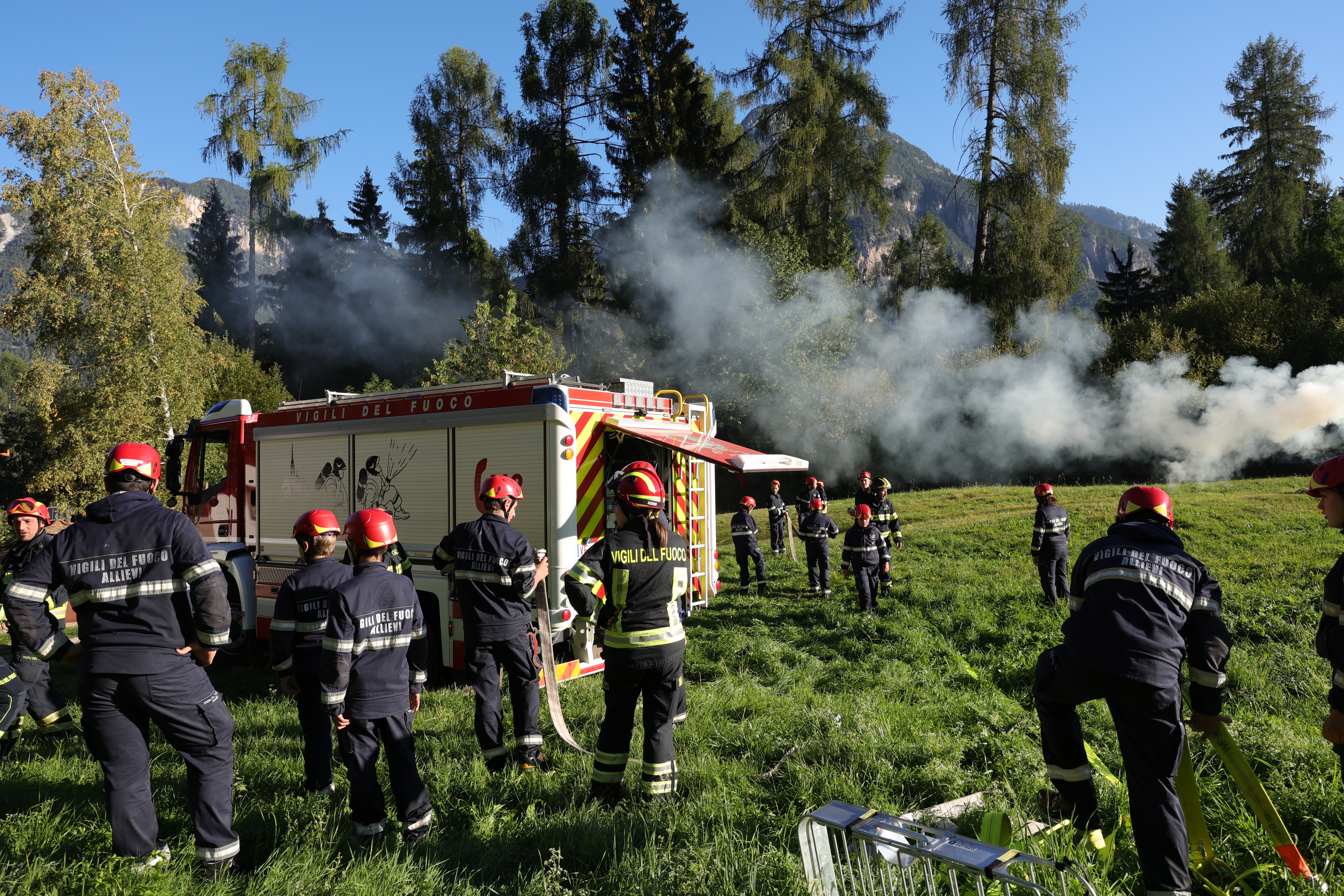 The volunteer firefighter trainees with hoses extinguish the fire in front of the fire truck