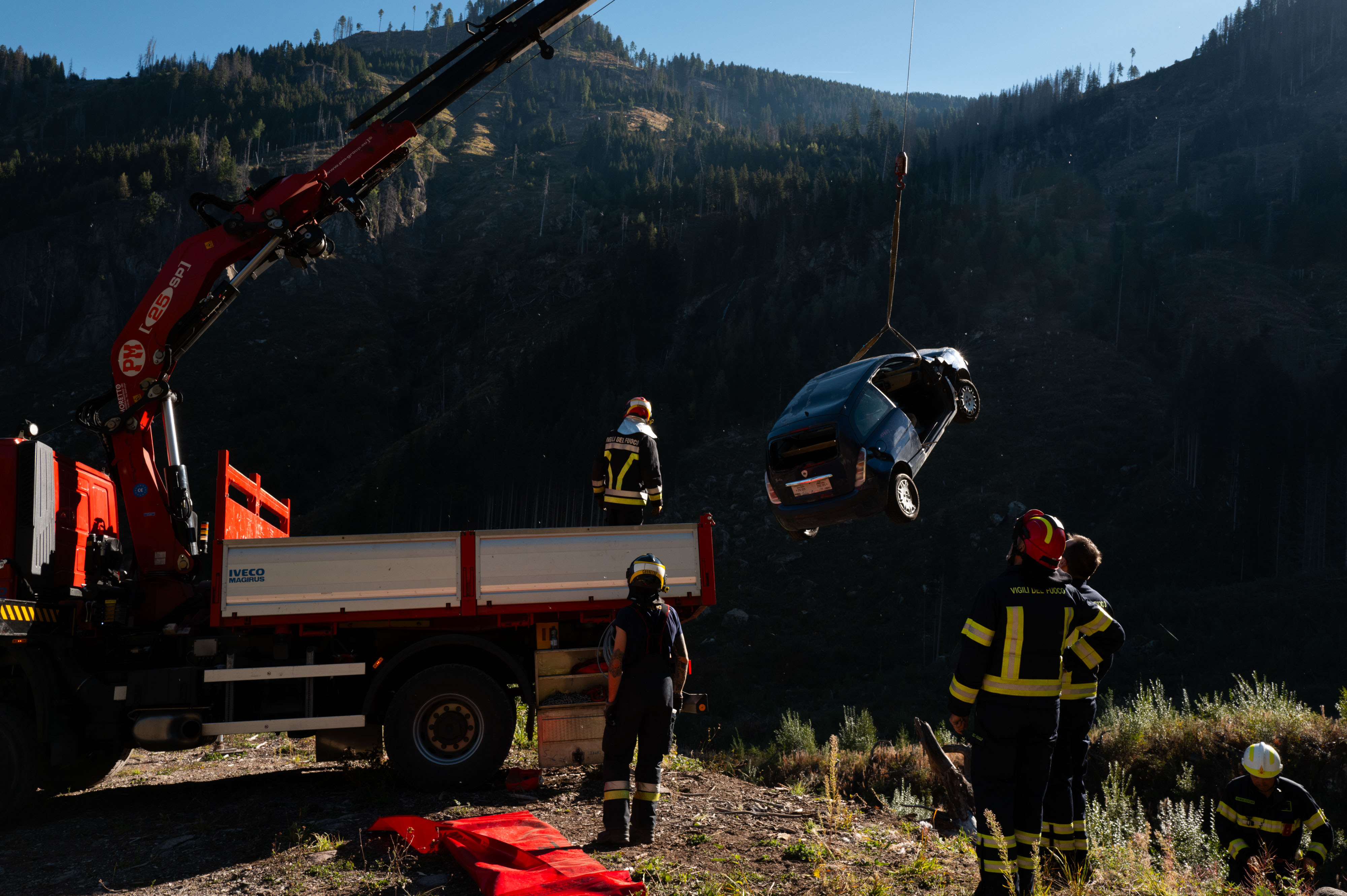 The truck crane lifts the car from the riverbed during the exercise