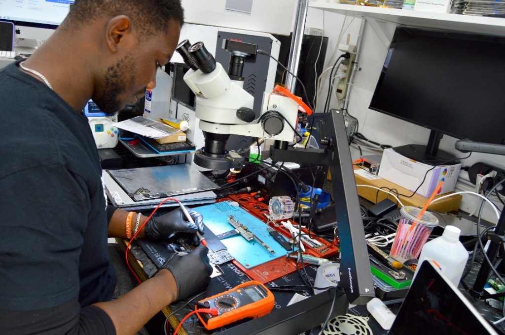 RepairRama technician testing PS5 circuit board under microscope Bronx