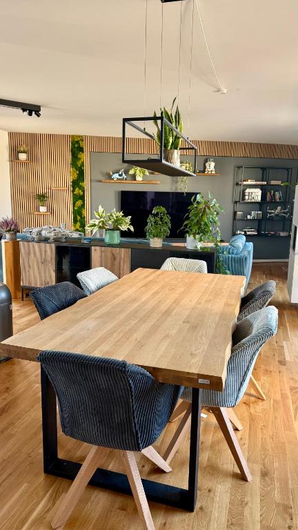 Weitläufiges Wohnzimmer des Penthouse Leipzig mit Designer-Holzwand und Smart-TV