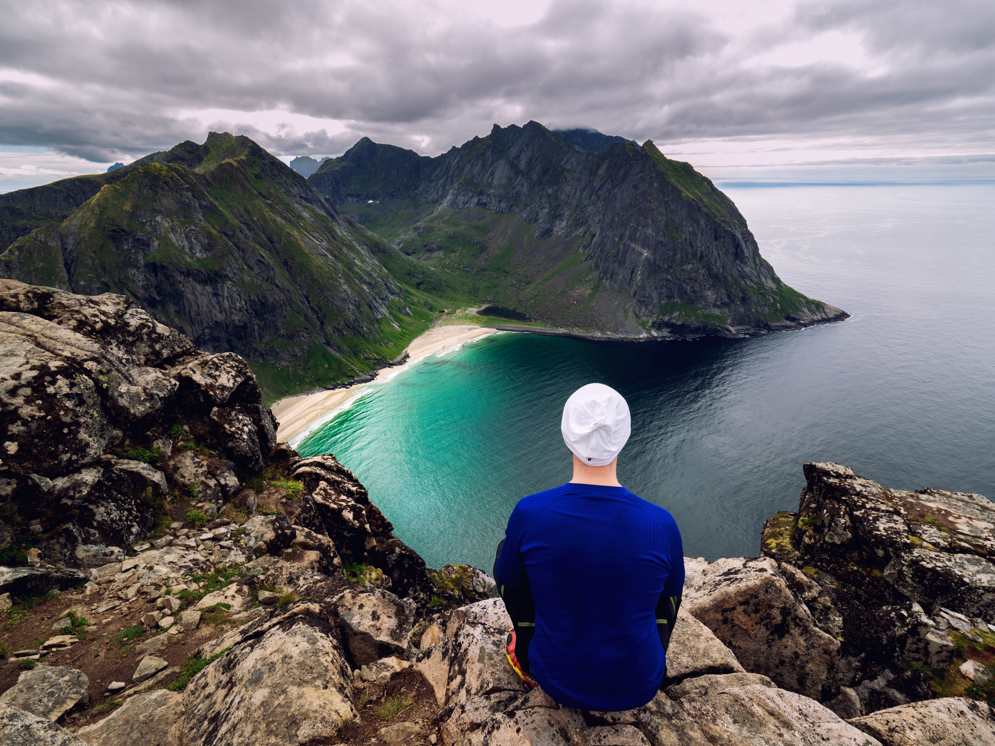 Person som sitter og ser ut over fjell og hav