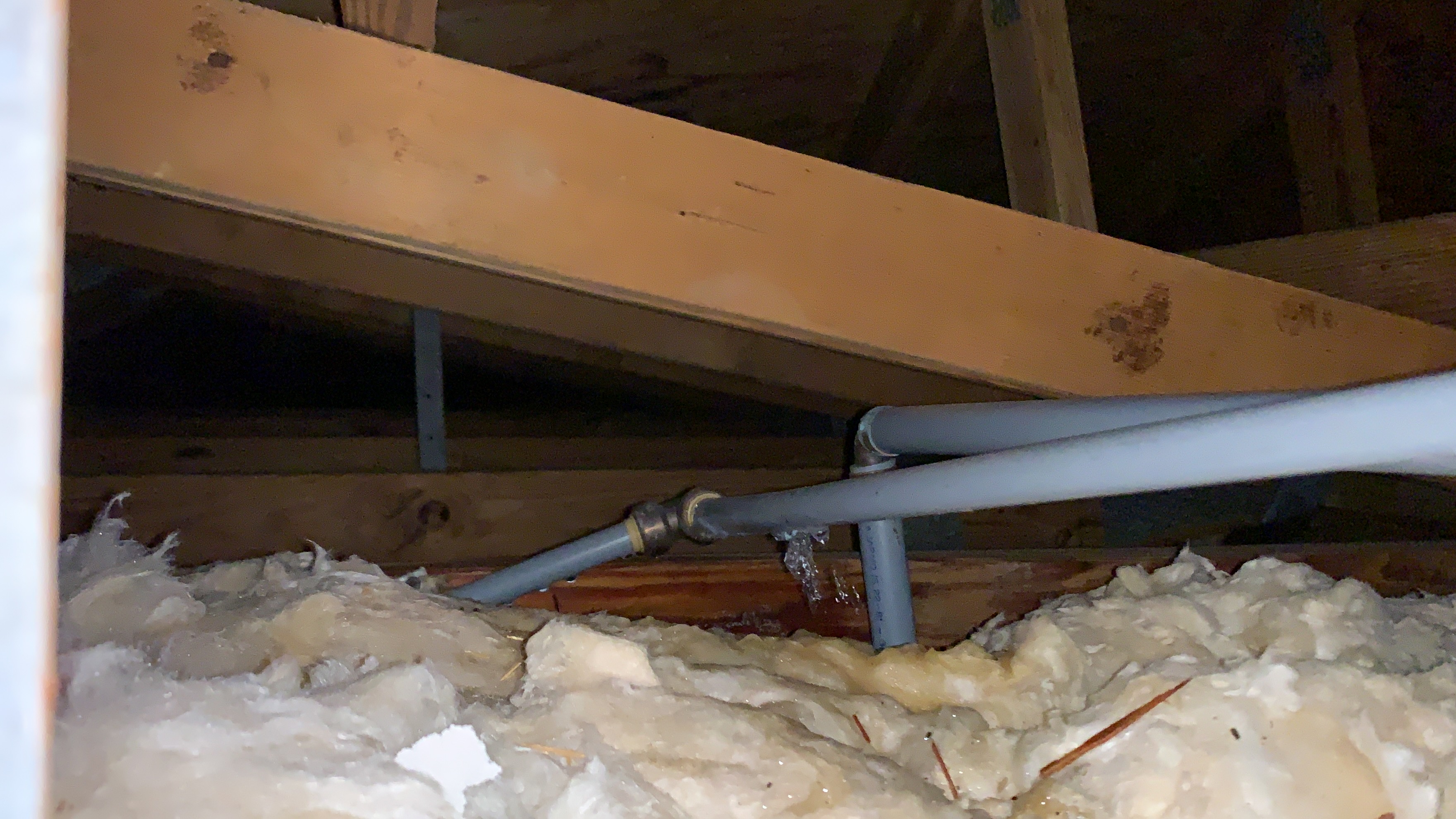 Active water leak dripping from a pipe fitting above attic insulation in a Davie home