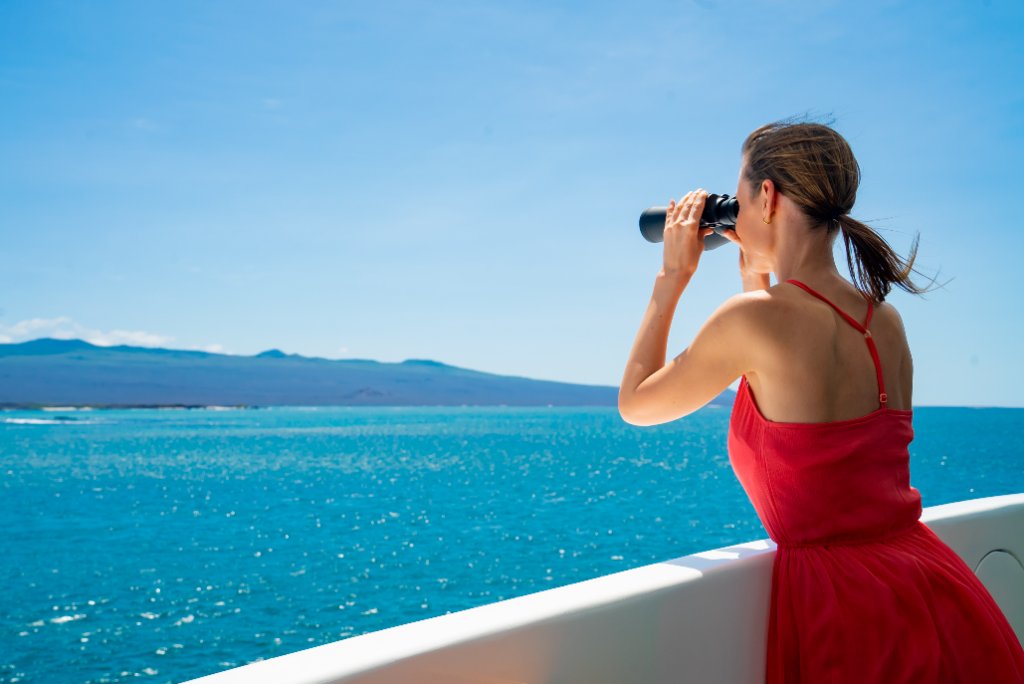 Guest viewing Kicker Rock through a telescope from the deck