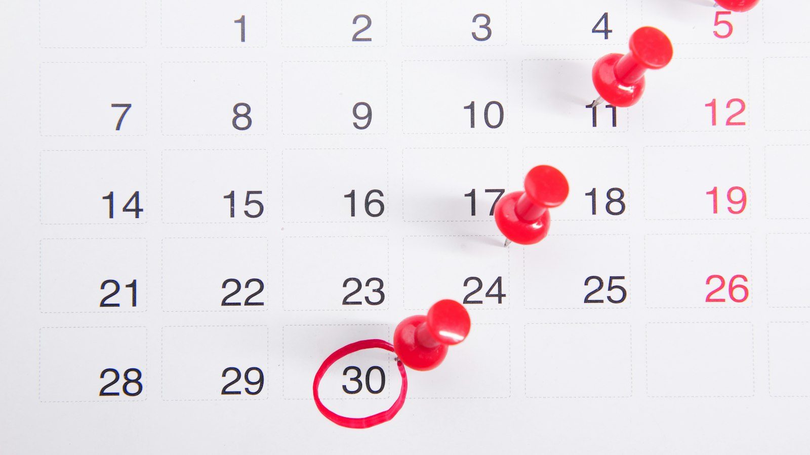 Monthly calendar with red push pins on several dates and the 30th circled in red