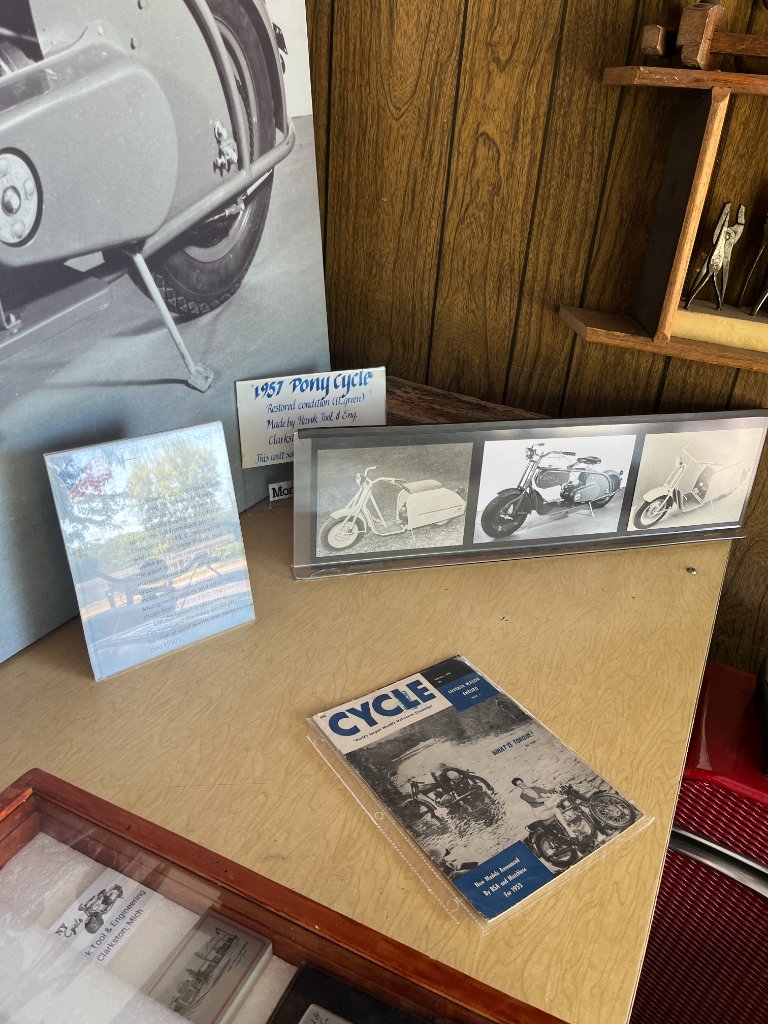 Display shelf with signage, magazine, and framed photos