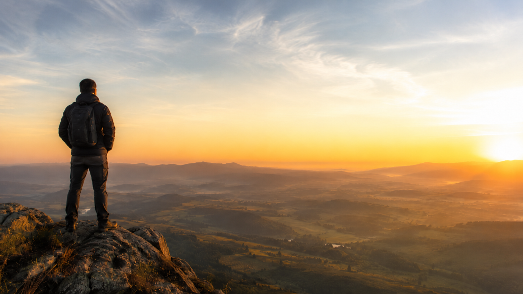 Man standing on a high viewpoint looking toward the sunrise