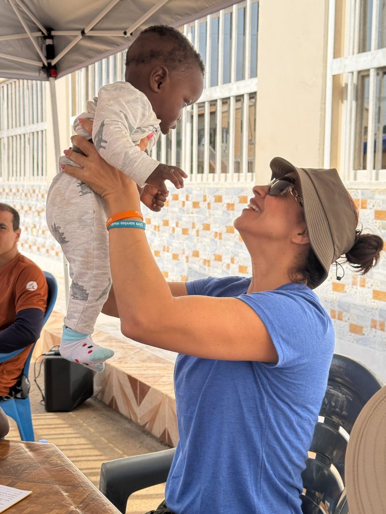 Voluntária brincando com bebê da comunidade - alegria e amor