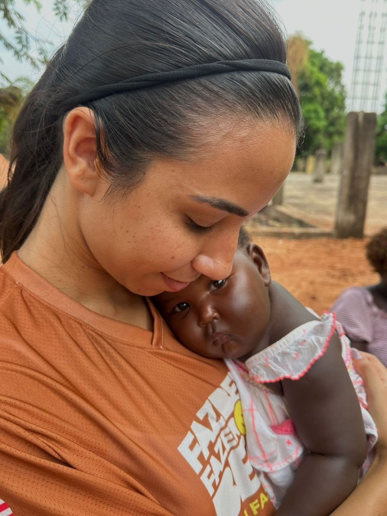 Voluntária segurando bebê da comunidade com muito amor e carinho