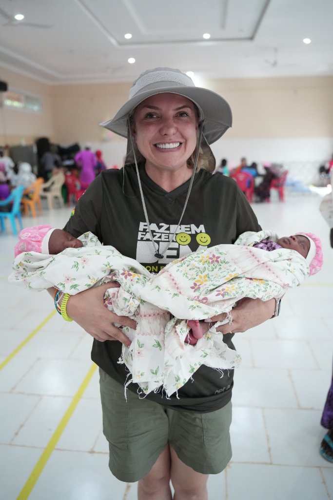 Voluntária segurando gêmeos recém-nascidos no atendimento de saúde
